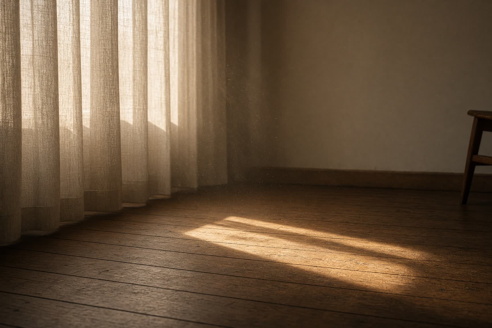 Afternoon light through linen curtains onto an empty floor.